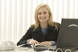 uśmiechnięta kobieta przy biurku z komputerem